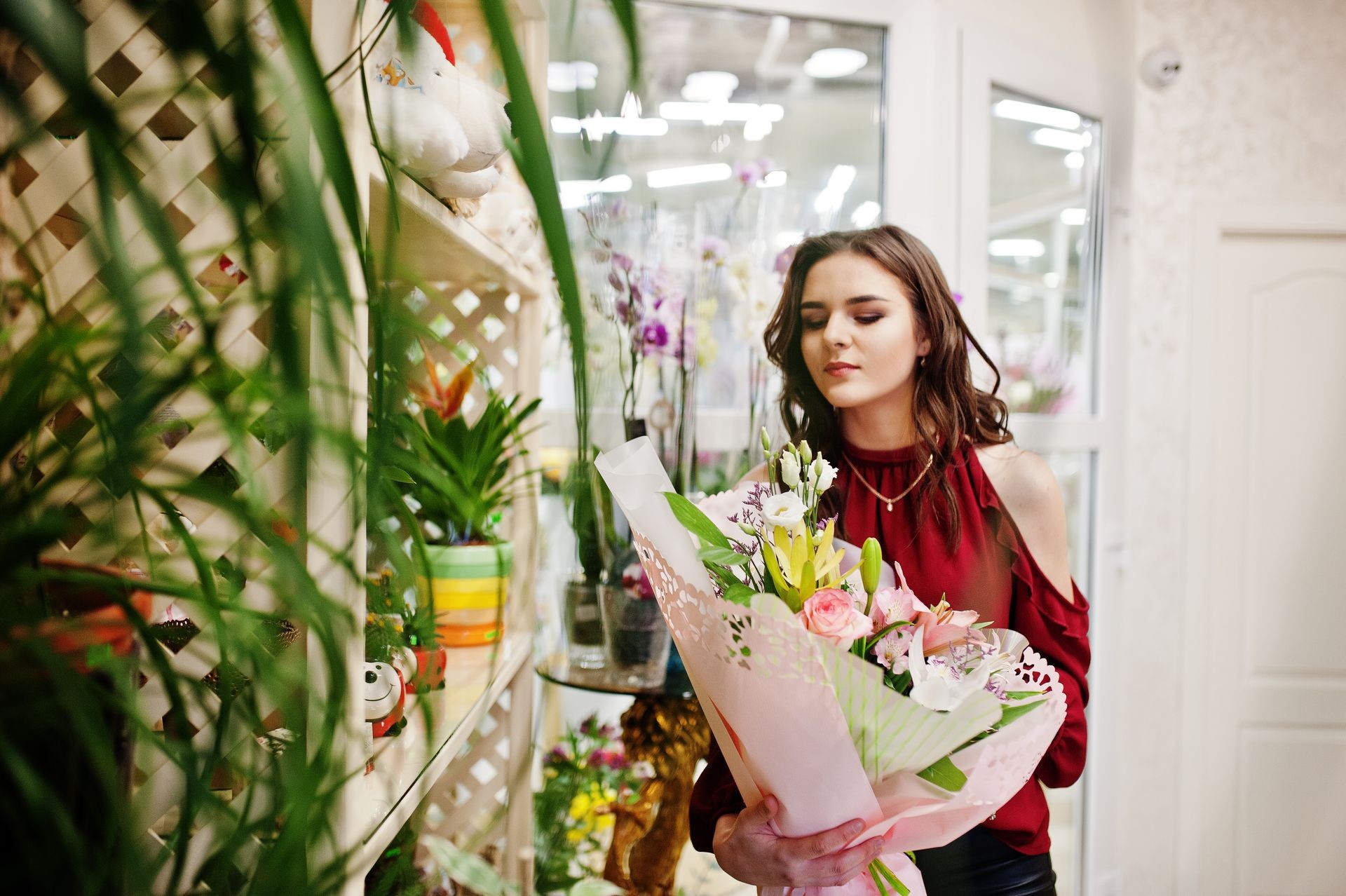 Brunette girl in red buy flowers at flower store.